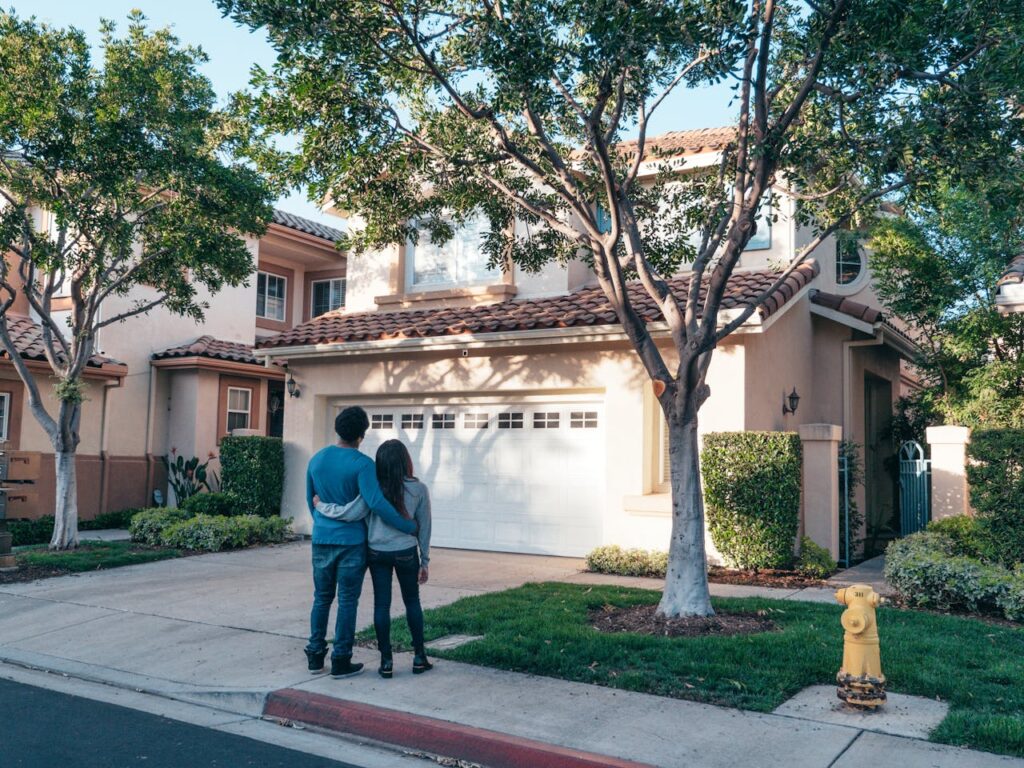 A young couple standing in front of their new house that was purchased with a conventional loan rather than a fix-and-flip loan. 