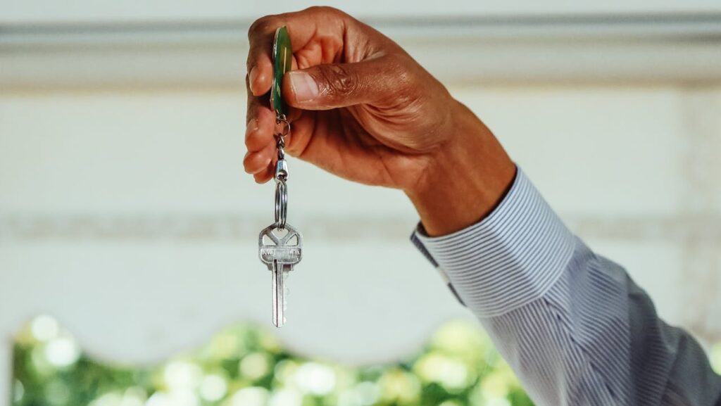 A hand holding up a key to a home purchased with a fix-and-flip loan. 