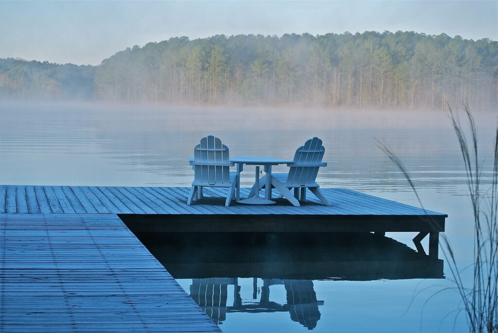 Two adirondack chairs are sitting on a dock at a cottage, which was financed using mortgages for vacation homes.