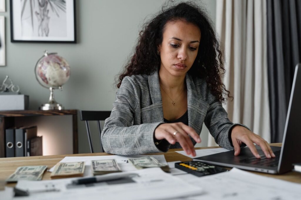 A woman is sitting at a desk, budgeting and calculating her finances to prepare to apply for a California construction loan.