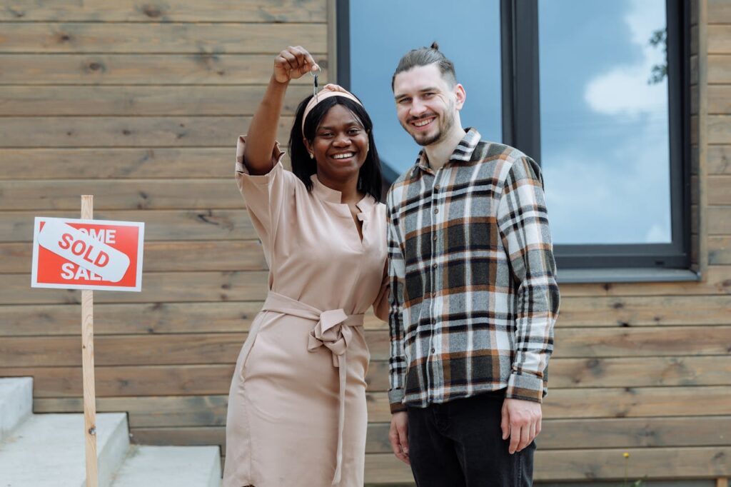 A couple is smiling while holding a key to their new house that was just purchased using a California interest-only mortgage.