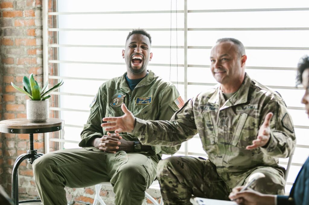 Two active-duty military service members are smiling and laughing. 