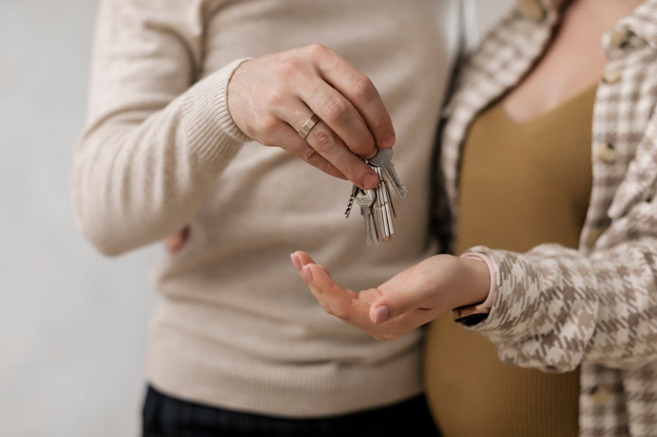 A couple is holding the keys to their new house after signing all of the paperwork and paying the mortgage closing costs.