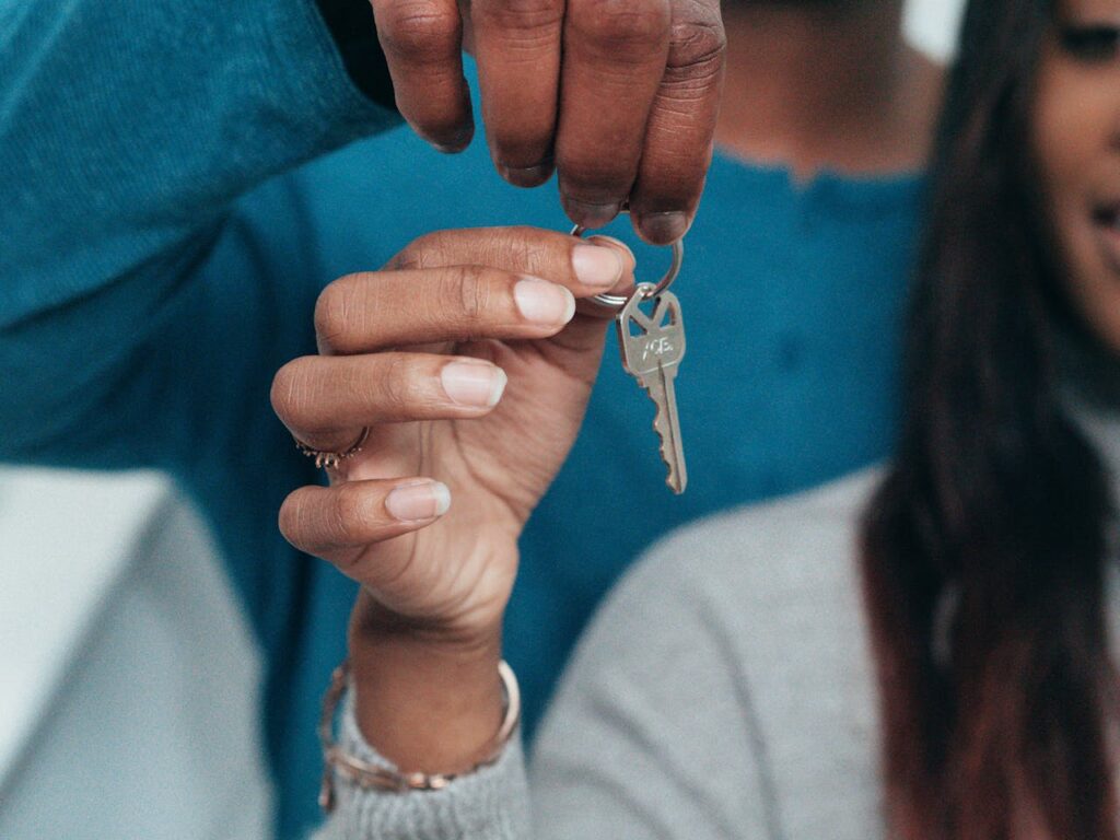 A couple is holding the key to their new house after following advice on how to improve your credit score. 