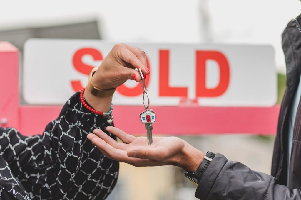 A realtor is handing over house keys to a new homeowner who purchase a house after interest rate cuts happened.