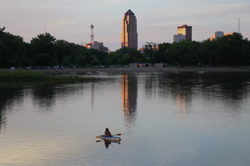 A person kayaking on the river with downtown Des Moines, Iowa in the background. 